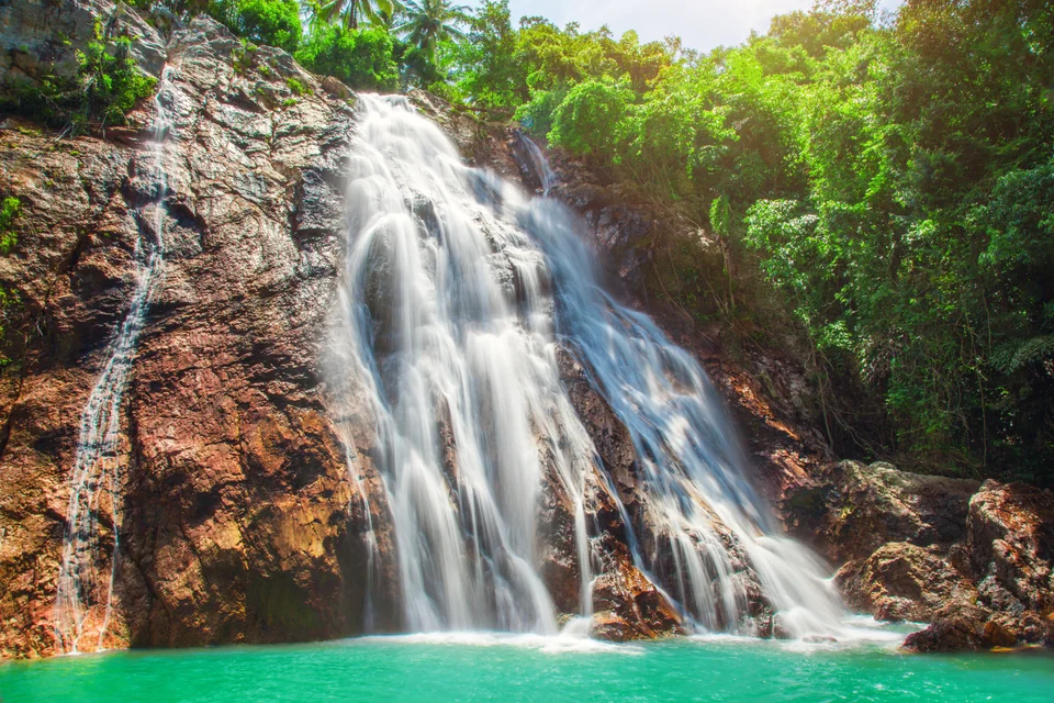 Na Muang Waterfall flowing into a pool surrounded by forest